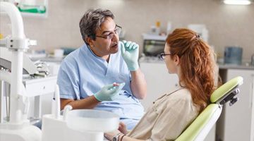 Dentist talking to woman in dental exam chair