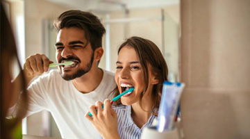 Man and woman brushing teeth together