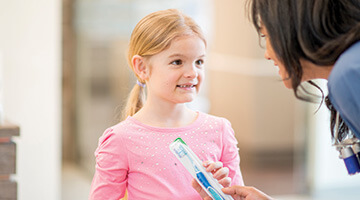 worker giving child a toothbrush