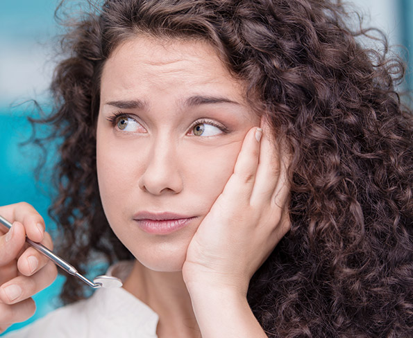 woman with curly hair holding cheek