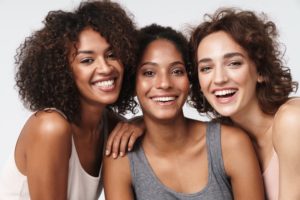 Three women standing close together smiling